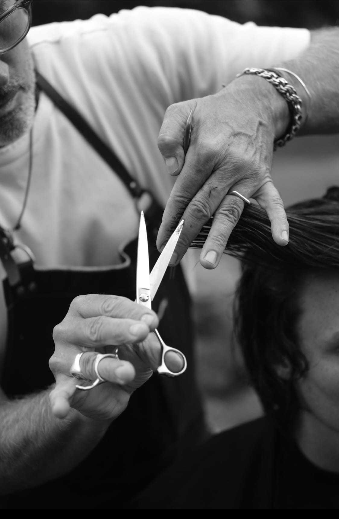 Barber skillfully cutting client's hair with scissors in black and white photo.